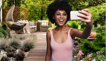 Frau macht mit ihrem Handy ein Selfie in einem schönen Garten
