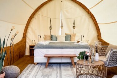 Großzügiges Glamping-Zelt von Strohboid, eingerichtet mit Bett und Couch