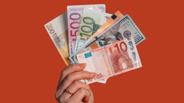 Eine weibliche Hand hält verschiedene aufgefächerte Euroscheine 